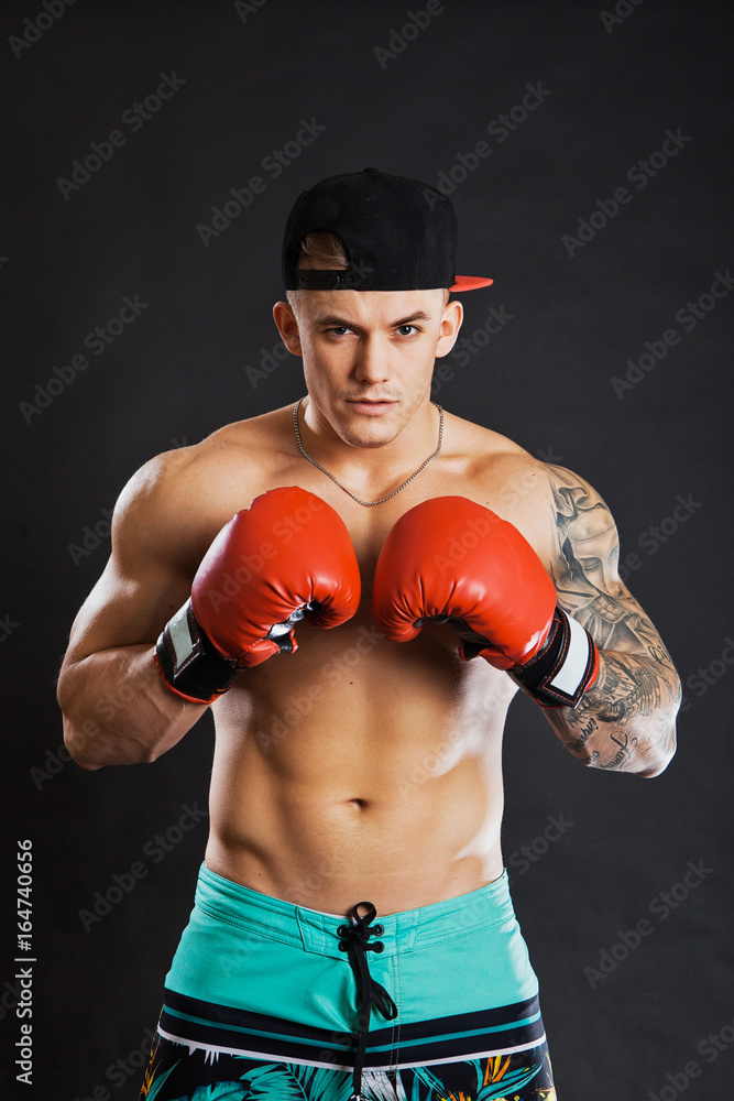 Young fitness model in boxing gloves. Muscular man Adobe Stock