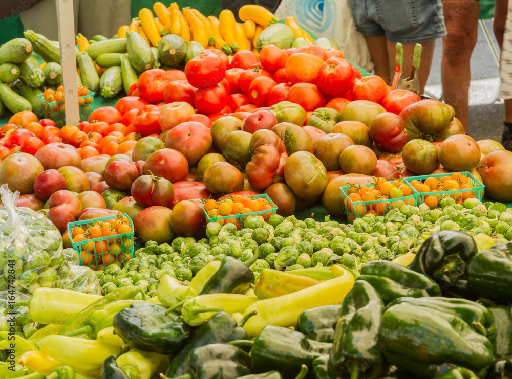 Farmer's market produce for sale at stand. Color horizontal photo of heirloom tomatoes, cherry tomatoes, brussel sprouts, zucchini, squashes, gypsy peppers and bell peppers are visible. Farmer's market produce for sale at stand. Color horizontal photo of heirloom tomatoes, cherry tomatoes, brussel sprouts, zucchini, squashes, gypsy peppers and bell peppers are visible.