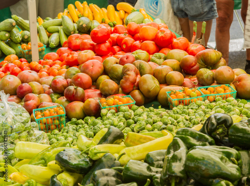 Farmer s market produce for sale at stand. Color horizontal photo of heirloom tomatoes  cherry tomatoes  brussel sprouts  zucchini  squashes  gypsy peppers and bell peppers are visible.