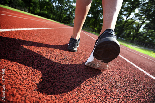 Red running track with female runner, close up on shoes