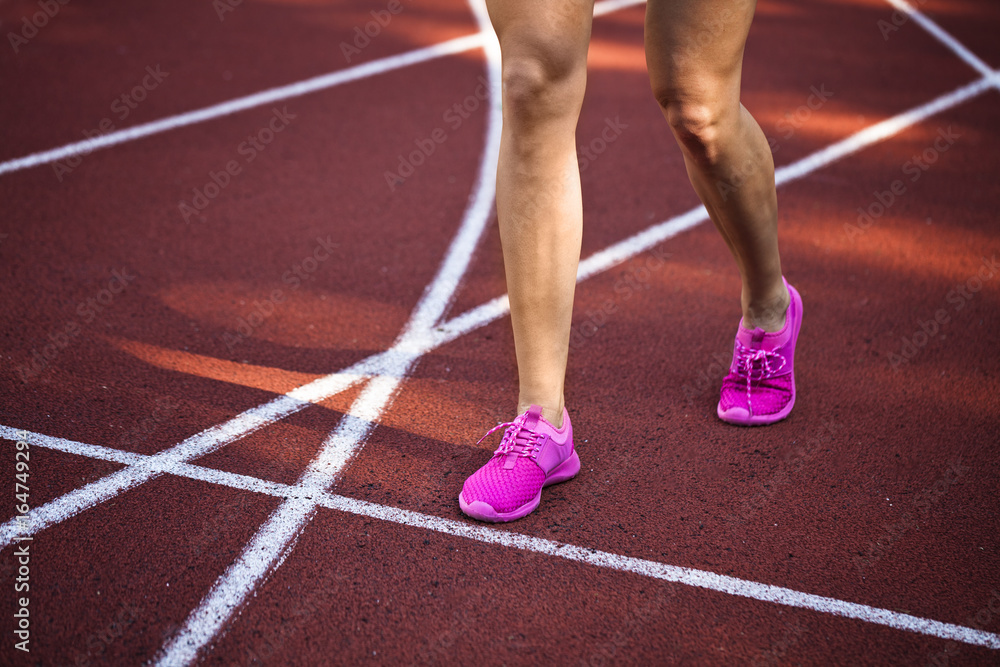 female athlete running in pink runners on a track
