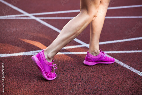 female athlete running in pink runners on a track