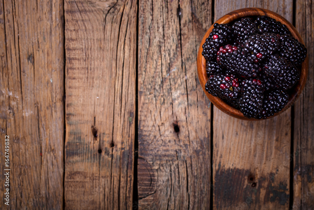 Blackberry Fresh in a wooden bowl.Berry on a wooden vintage background.Food or Healthy diet concept.Super Food.Vegetarian.Top View.Copy space for Text.selective focus.