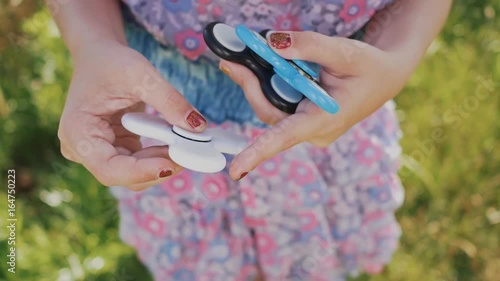 The girl is holding spinners white, blue and black colour. Stress relieving toy. photo