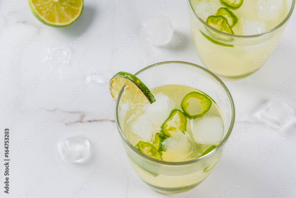 Mexican traditional refreshing drink Fresh Lime and Jalapeno Margarita with tequila, hot pepper and lime (lemon). On a white marble kitchen table. Copy space Mexican traditional refreshing drink Fresh Lime and Jalapeno Margarita with tequila, hot pepper and lime (lemon). On a white marble kitchen table. Copy space