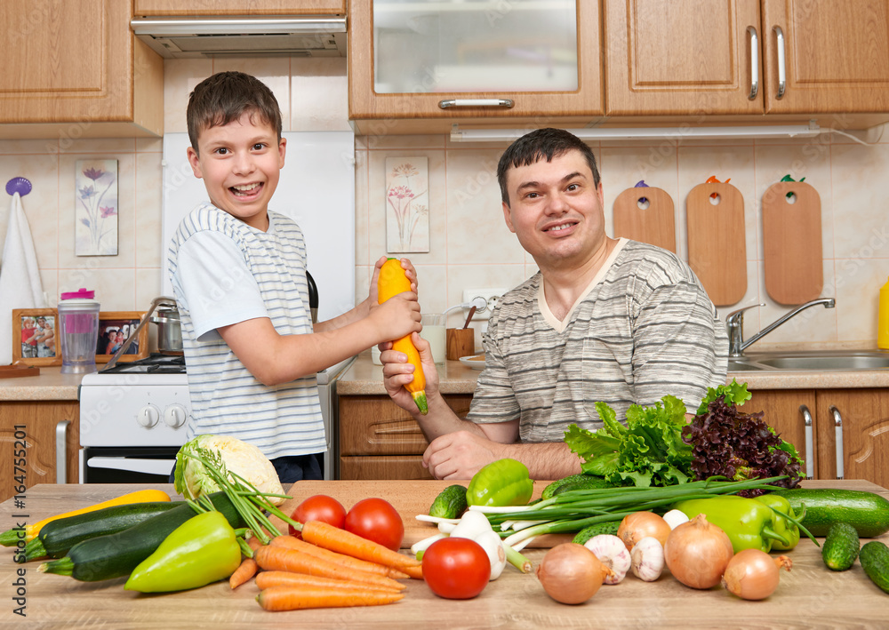 Father and son having fun with vegetables in home kitchen interior. Man and child. Fruits and vegetables. Healthy food concept Father and son having fun with vegetables in home kitchen interior. Man and child. Fruits and vegetables. Healthy food concept