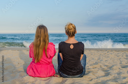 Two girls are sitting on the beach