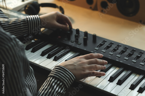 A woman in a striped shirt plays the synthesizer and tunes it.