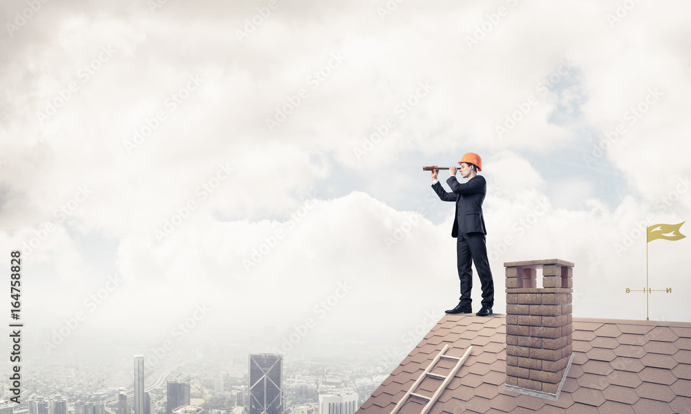 Engineer man standing on roof and looking in spyglass. Mixed med