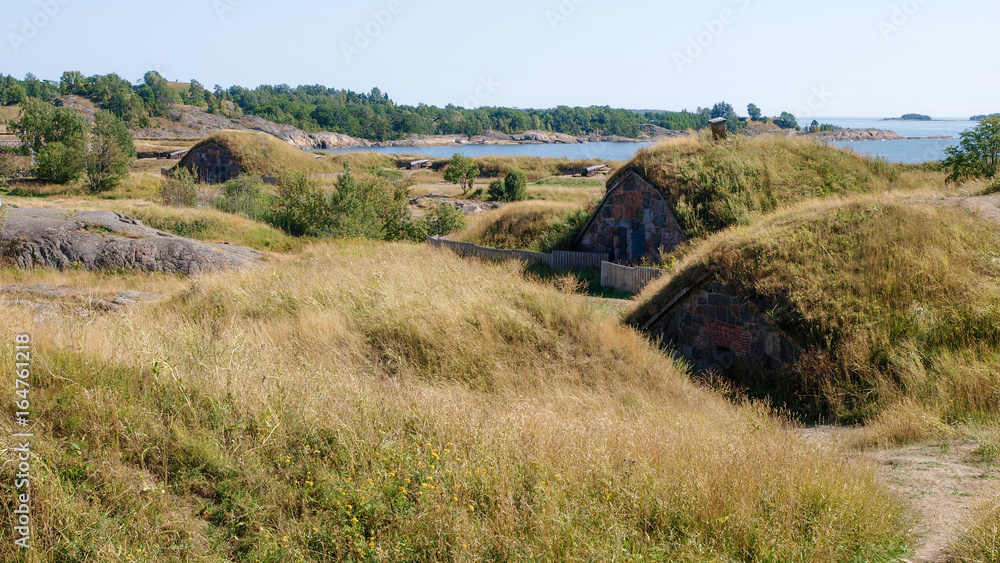 Fototapeta premium Old scandinavian earthen homes integrated into the rolling hills with the baltic sea in the back