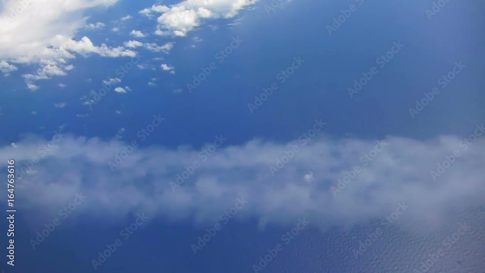 Flying in airplane over Pacific ocean and clouds showing Earth's atmosphere, airplane banks revealing contrails from another jet.. Flying in airplane over Pacific ocean and clouds showing Earth's atmosphere, airplane banks revealing contrails from another jet..