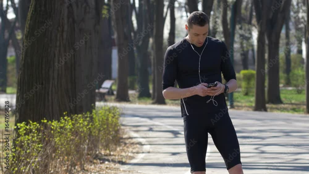 Professional athlete with smartphone and hands free checking fitness trackers while resting Professional athlete with smartphone and hands free checking fitness trackers while resting