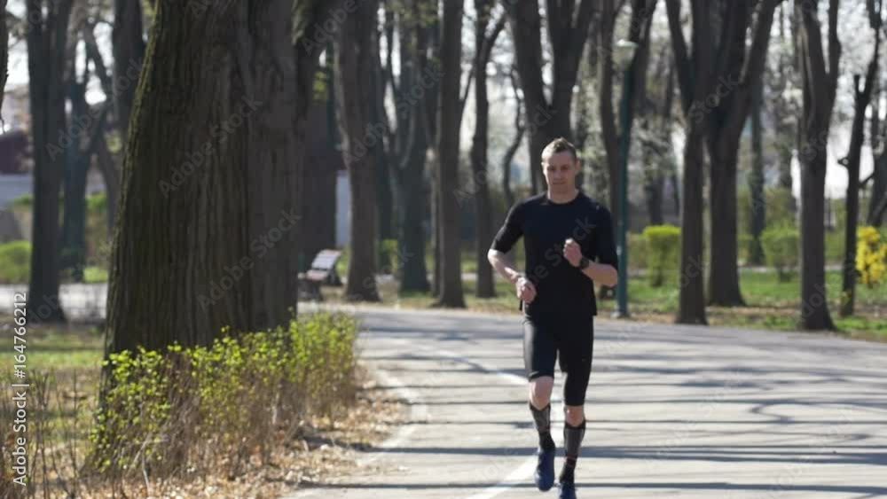 Slow motion of young fit sportive catching breath after jogging in the park Slow motion of young fit sportive catching breath after jogging in the park