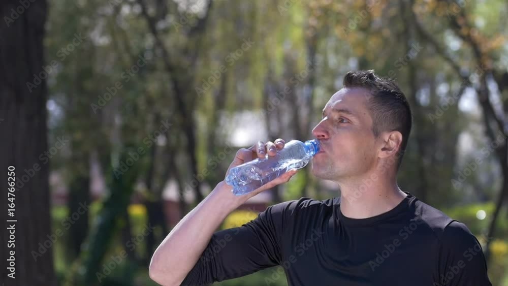 Thirsty jogger pouring water over his face and cooling himself after jog training in slow motion Thirsty jogger pouring water over his face and cooling himself after jog training in slow motion