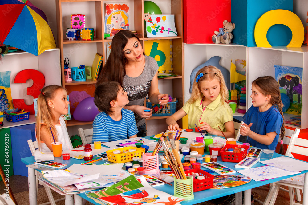 Small students with teacher finger painting in art school class. Mom ...