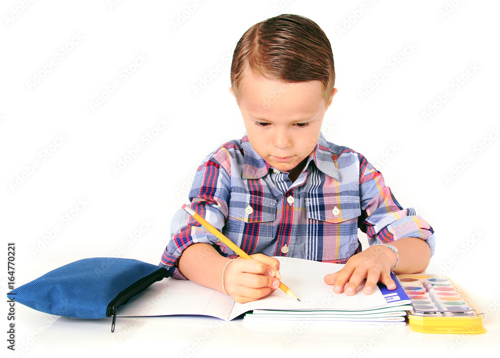 Five year old boy doing his homework. Studio isolated on white. Five year old boy doing his homework. Studio isolated on white.