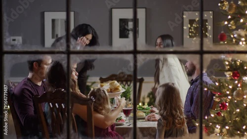 Medium zoom out shot of family eating meal on Christmas behind window / Cedar Hills, Utah, United States