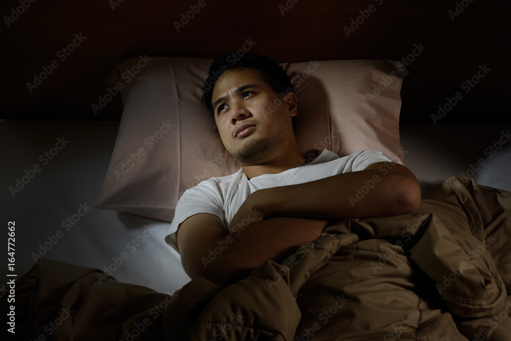 Depressed man suffering from insomnia lying in bed Depressed man suffering from insomnia lying in bed