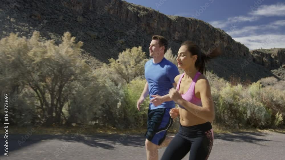 Medium slow motion tracking shot of couple running in neighborhood / Antimony, Utah, United States Medium slow motion tracking shot of couple running in neighborhood / Antimony, Utah, United States