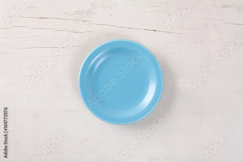 Top view of empty blue plate put on white wood table with space for copy.