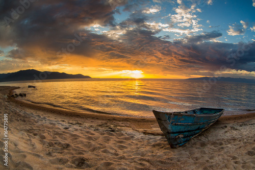 Old wooden boat on a sandy beach at sunset. Baikal 2017