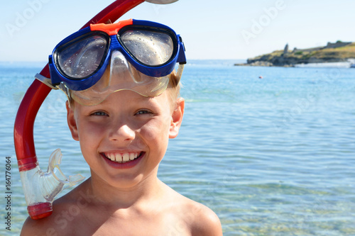 Joyful boy on the beach in a mask for scuba diving.