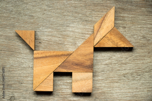 Tangram puzzle in dog shape on wooden background