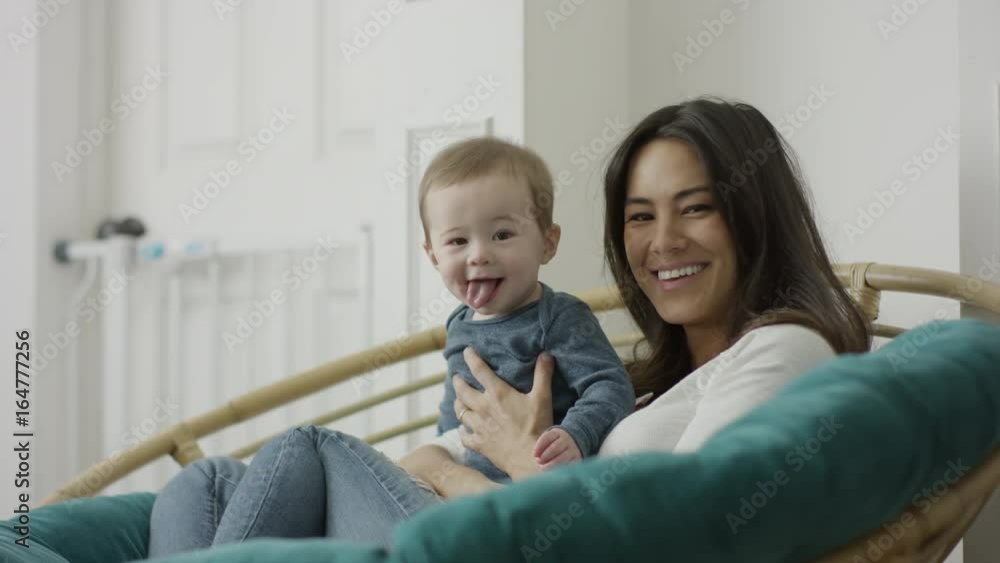 Medium shot of mother sitting holding baby son with tongue out / Provo, Utah, United States Medium shot of mother sitting holding baby son with tongue out / Provo, Utah, United States