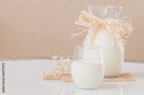 A glass of milk and a pitcher of milk on marble table.