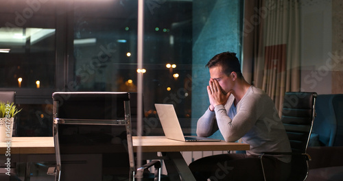 man working on laptop in dark office