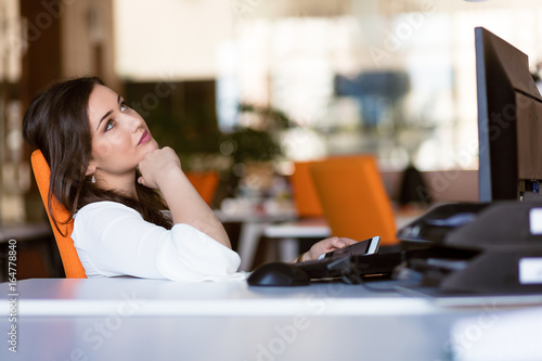 Фотография Happy pensive businesswoman planning and looking sideways at office