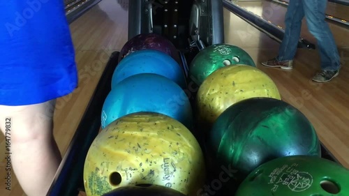 Someone choosing a bowling ball in a bowling alley