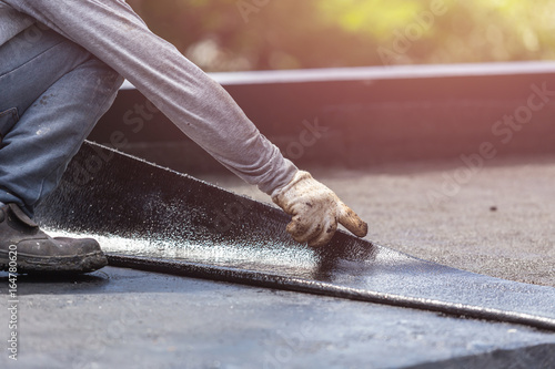 Group of worker installing tar foil on the rooftop of building. Waterproof system by gas and fire torching photo