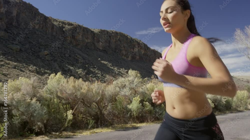 Medium low angle tracking shot of woman running in neighborhood / Antimony, Utah, United States Medium low angle tracking shot of woman running in neighborhood / Antimony, Utah, United States