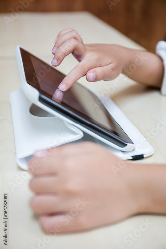Child's hands playing tablet computer