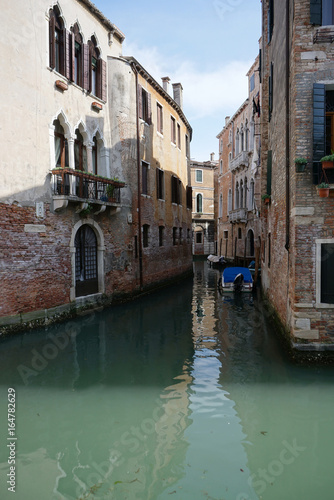 Beautiful building along the canal with tourist walking around in Venice