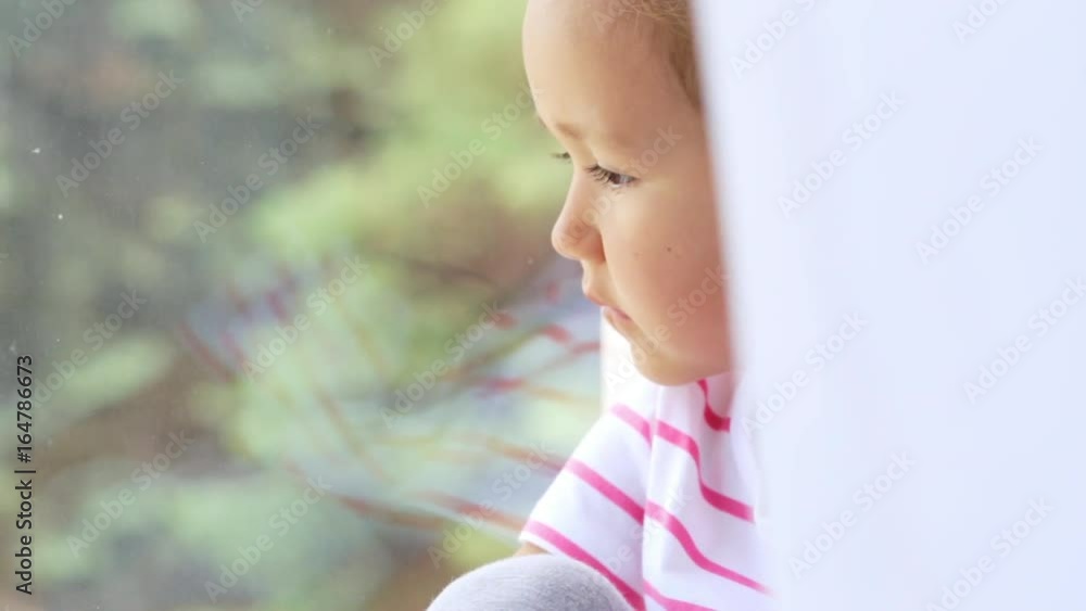 Close up of hands on knees of cute little girl sitting on windowsill of window.
