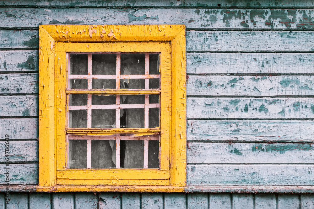 Obraz premium yellow window on green wooden wall of abandoned house