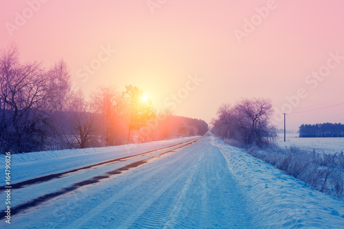 Rural winter landscape. Sunrise over snowy road