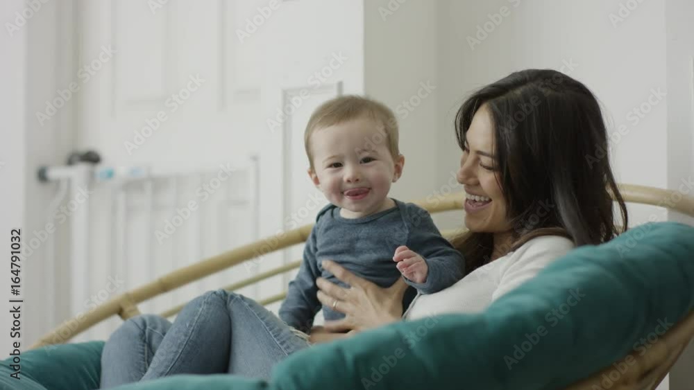 Medium shot of mother sitting holding baby son with tongue out / Provo, Utah, United States Medium shot of mother sitting holding baby son with tongue out / Provo, Utah, United States