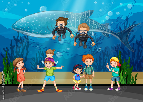 Kids looking at whale and divers in aquarium