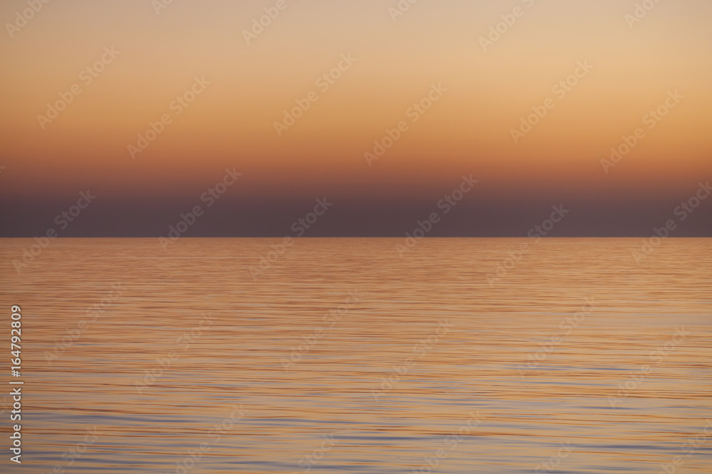 Smooth Sea Sunset Texture / Warm dusk seascape over the smooth ocean and clear sky horizon. 