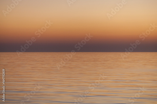 Smooth Sea Sunset Texture   Warm dusk seascape over the smooth ocean and clear sky horizon. 