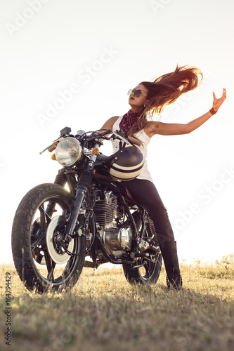 Fototapeta Naklejka Na Ścianę i Meble -  Girl on a motorcycle. She is beautiful, posing on a motorcycle at sunset