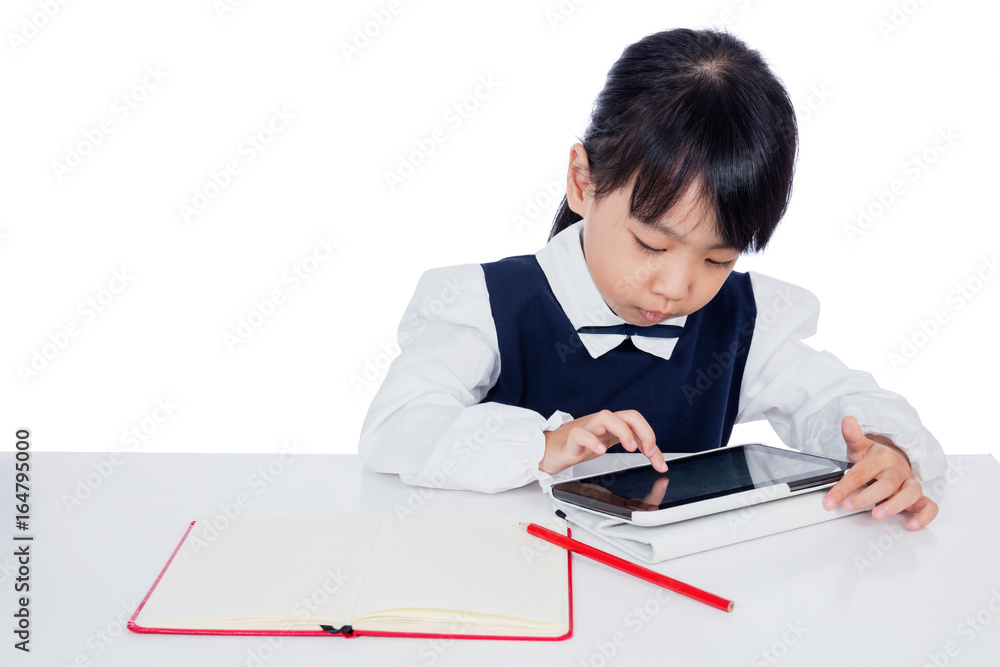 Asian Chinese little girl in uniform studying with tablet computer Asian Chinese little girl in uniform studying with tablet computer