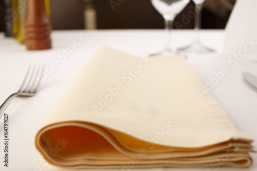 Fork and table knife with napkin arranged in elegant setting, Wineglass in the background, Selective focus with soft light