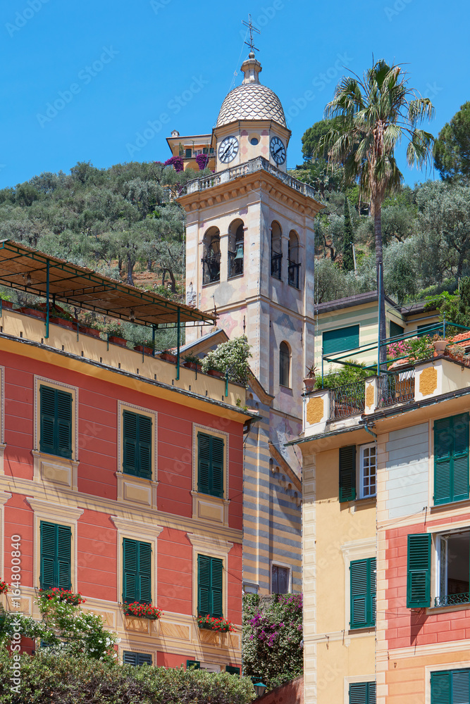 Portofino typical colorful houses and Divo Martino church bell tower with palm tree, Italy