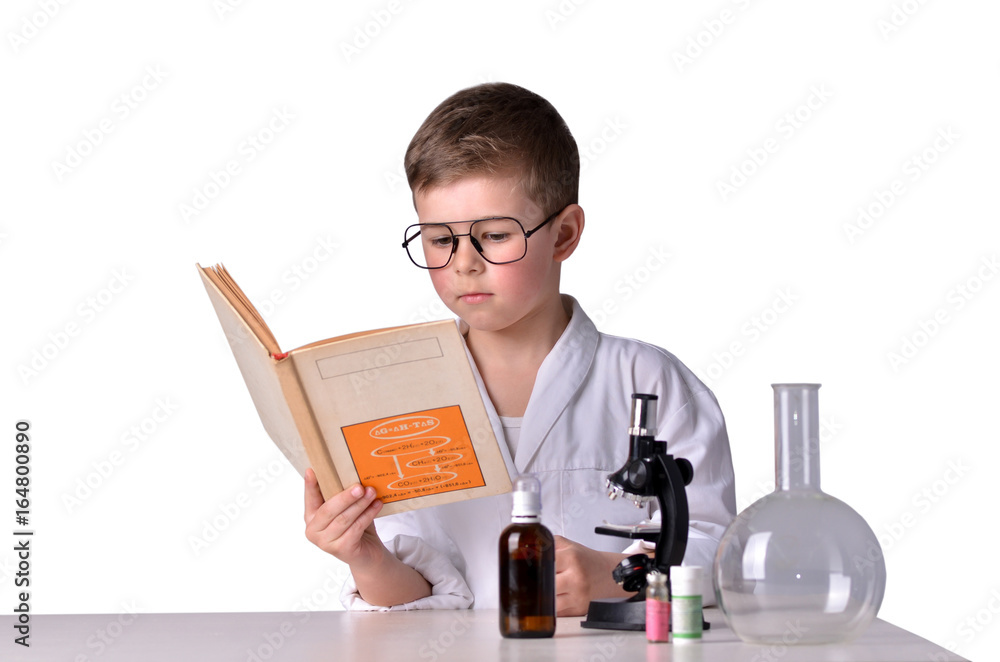 Scientist boy reads book at the desk in the lab Scientist boy reads book at the desk in the lab