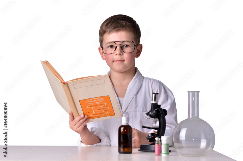Scientist boy in glasses at the desk with a book in his hand Scientist boy in glasses at the desk with a book in his hand
