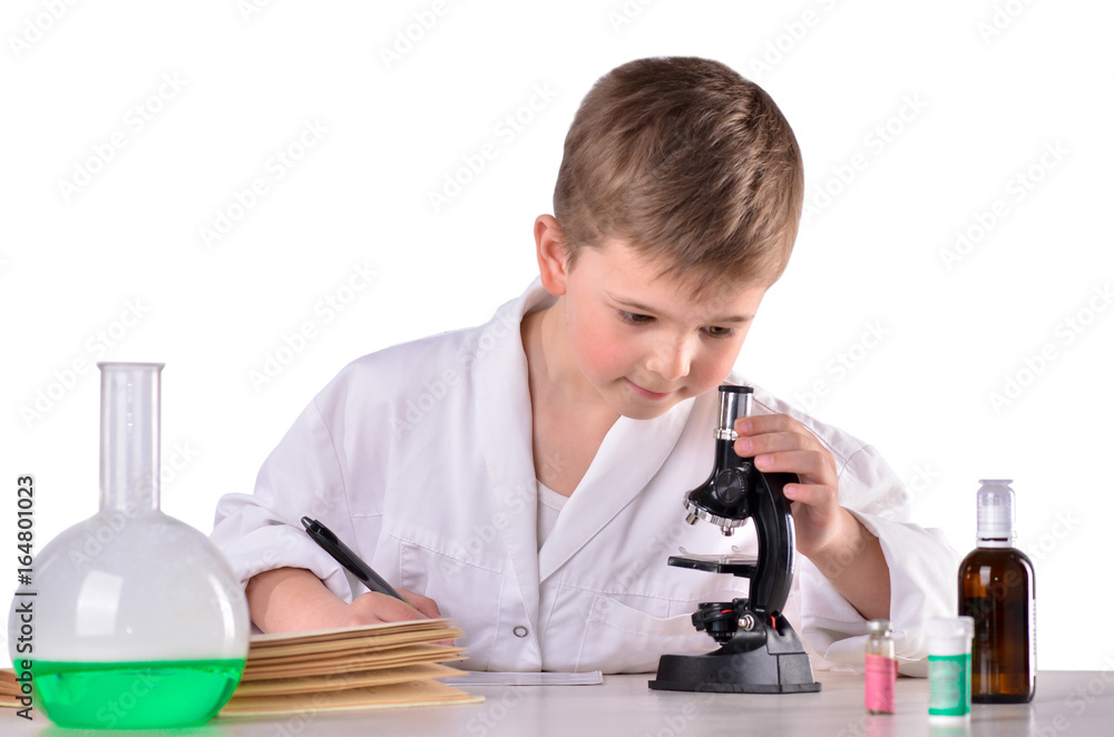Scientist boy at the desk in the lab write research results Scientist boy at the desk in the lab write research results